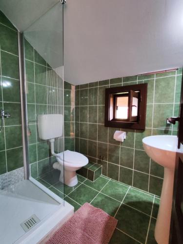 a green tiled bathroom with a toilet and a sink at Pensiunea Orion in Costinesti