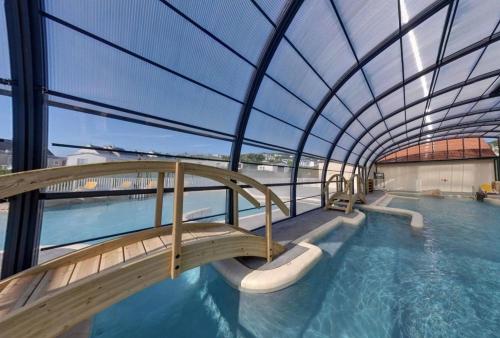 a large indoor swimming pool with a glass roof at MOBILHOME camping LA FALAISE in Équihen-Plage