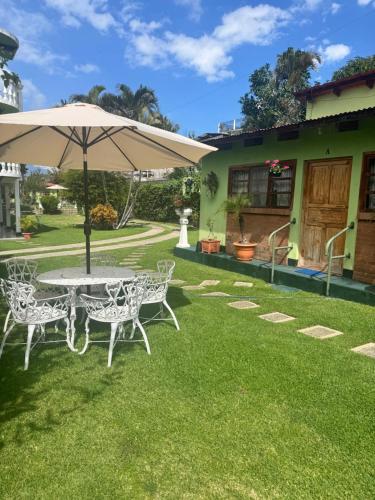 a table and chairs with an umbrella on a lawn at Hotel Posada Kamol Bey in Panajachel