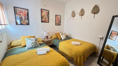two beds in a room with yellow and blue at Casa Rural Zahara 21 in Zahara de la Sierra