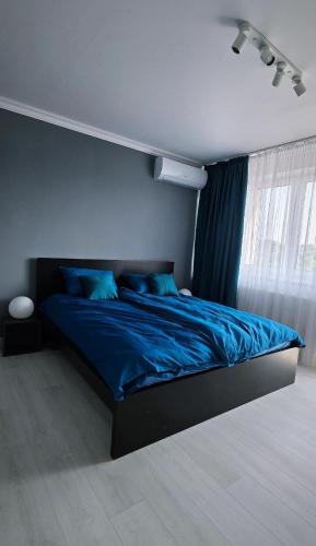 a bedroom with a bed with blue sheets and a window at RVR Apartmanhàz in Sárospatak