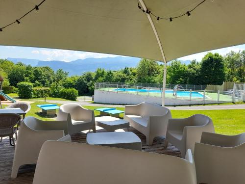 a patio with tables and chairs and a pool at Camping Le Balcon de Chartreuse in Miribel-les-Échelles