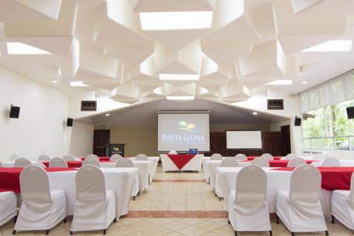 a conference room with white tables and chairs and a screen at Hotel Punta Leona in Jacó