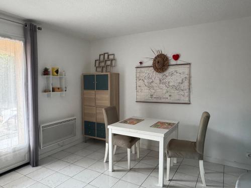 une salle à manger avec une table et des chaises blanches dans l'établissement Appart rez de jardin 2 à 6 personnes, à Six-Fours-les-Plages