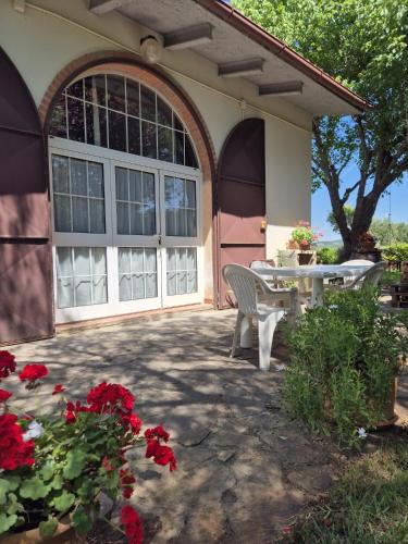 a house with a patio with a table and red flowers at Casa Alima in Suvereto