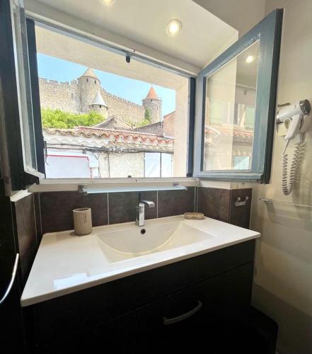 une salle de bain avec un lavabo et une fenêtre dans l'établissement La Loge des Remparts, à Carcassonne
