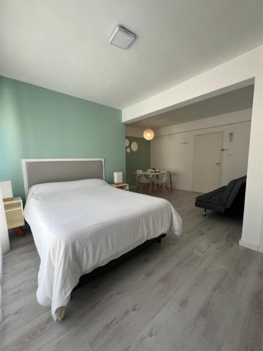 a bedroom with a large white bed and a table at Luminoso departamento en el centro de la ciudad in Mar del Plata