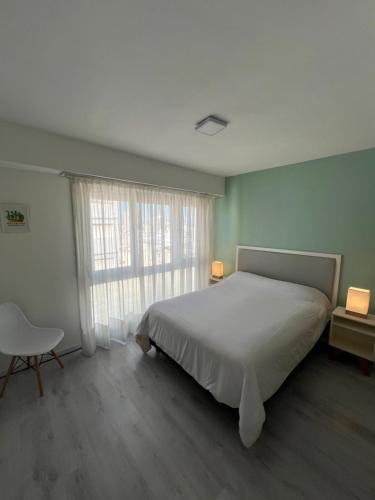 a bedroom with a bed and a chair and a window at Luminoso departamento en el centro de la ciudad in Mar del Plata