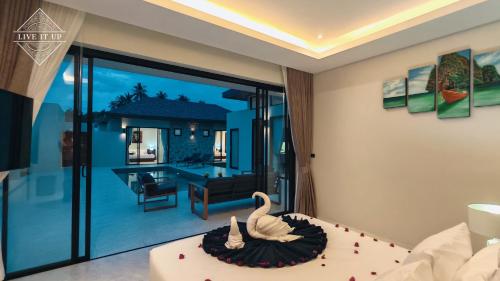 a bedroom with two swans on a bed and a living room at Santi Tara Villas in Amphoe Koh Samui