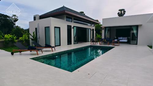 a villa with a swimming pool in front of a house at Santi Tara Villas in Amphoe Koh Samui