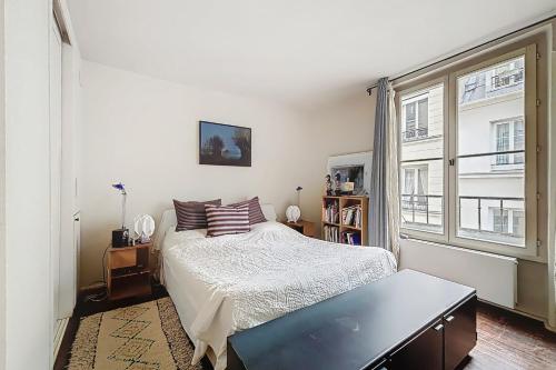 une chambre avec un lit et une grande fenêtre dans l'établissement Cosy apartment near Bastille, à Paris