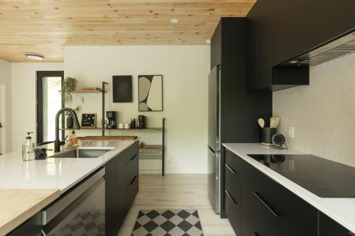 a kitchen with black cabinets and white counter tops at Forest Refuge - Fire - HotTub - Tremblant 15 min in La Conception