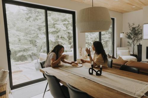 two women sitting at a table eating food at Forest Refuge - Fire - HotTub - Tremblant 15 min in La Conception