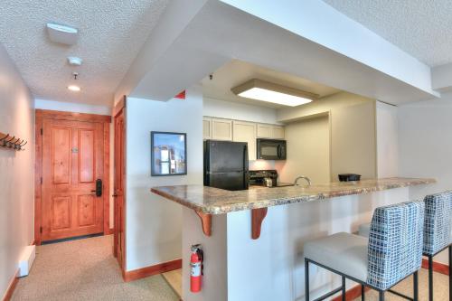 a kitchen with a counter and a bar with chairs at Wedgewood Lodge in Breckenridge