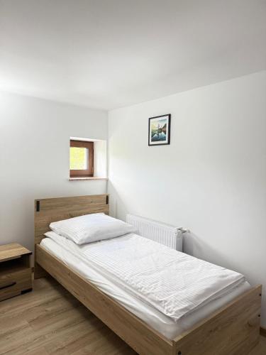 a bed in a bedroom with a white wall at Apartamenty Wadowity- Energylandia Zator in Wadowice