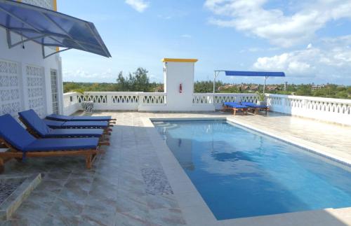 una piscina con tumbonas azules junto a un edificio en Casa Marabella C3, en Diani Beach