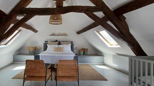 a attic bedroom with a bed and two chairs at AUX BRIQUES ROUGES Au pied du château et à 4 km du zoo de Beauval in Saint-Aignan