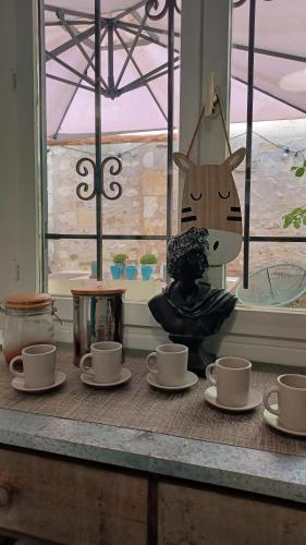 a table with cups and a statue of a cat at AUX BRIQUES ROUGES Au pied du château et à 4 km du zoo de Beauval in Saint-Aignan