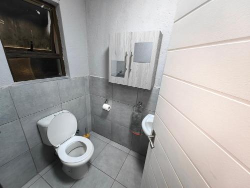 a small bathroom with a toilet and a window at Azrisi Apartments in Kempton Park