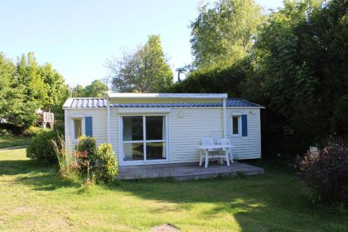 a small white shed with a table and chairs in a yard at Camping Le Balcon de Chartreuse in Miribel-les-Échelles