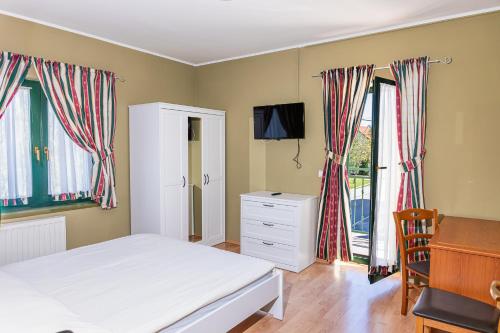 a bedroom with a bed and a desk and windows at Breza Ravna Gora Rooms and Bistro in Ravna Gora
