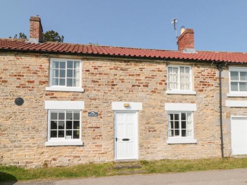 an old brick house with white doors and windows at Brookleigh in Hutton le Hole