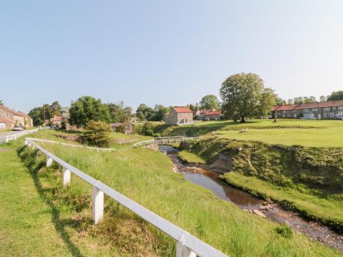 a bridge over a river next to a field at Brookleigh in Hutton le Hole