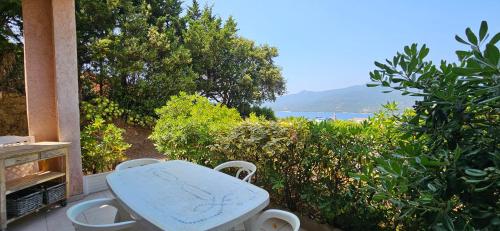 a table and chairs on a porch with a view of the ocean at T1 Pinedda, Studio confort-Vue mer- Calme & soleil in Propriano