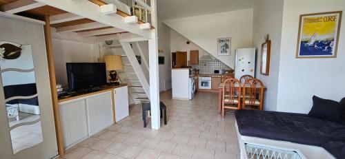 a living room with a staircase and a kitchen at T1 Pinedda, Studio confort-Vue mer- Calme & soleil in Propriano