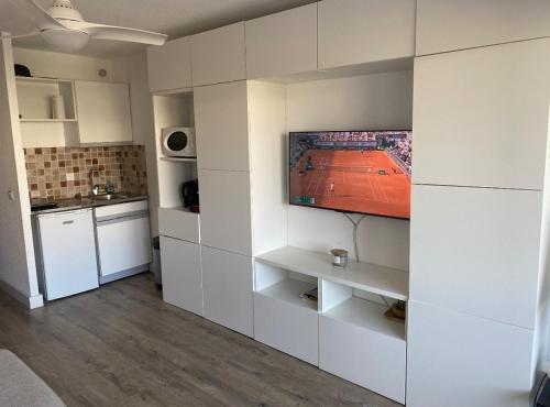 Il comprend une cuisine blanche dotée d'une télévision murale. dans l'établissement Studio cabine avec parking, au Grau-du-Roi