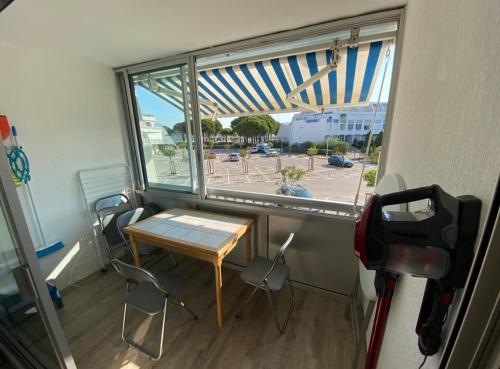 une table et des chaises dans une pièce avec une fenêtre dans l'établissement Studio cabine avec parking, au Grau-du-Roi