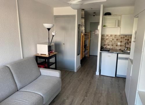 un salon avec un canapé et une cuisine dans l'établissement Studio cabine avec parking, au Grau-du-Roi