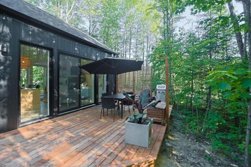 a patio with an umbrella and a table and chairs at Woodland - Terrace - Fire pit - 15min Tremblant in La Conception