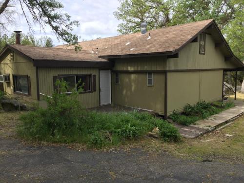 a small green house with a garage at Mountain Trail Lodge and Vacation Rentals in Oakhurst