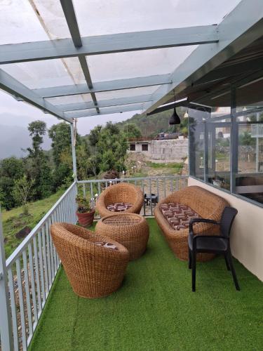 a patio with wicker chairs and tables on a balcony at Shivalik Dharohar ,barkot in Sar