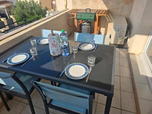 - une table avec des assiettes et des ustensiles sur un balcon dans l'établissement Appartement bord de mer, à Le Castellas