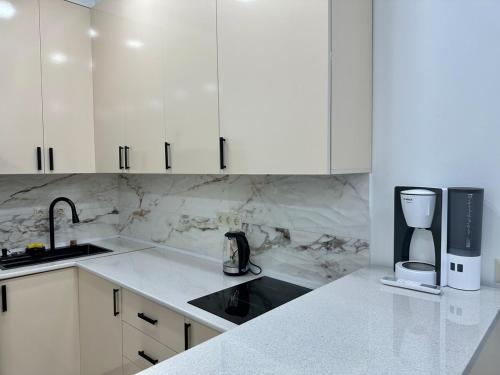 a white kitchen with white cabinets and a sink at Tsikhisdziri Apt Sleeps 5 in Tsikhisdziri