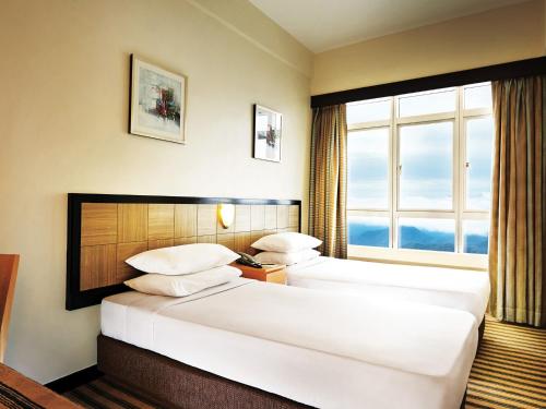 two beds in a hotel room with a window at Resorts World Genting - First World Hotel in Genting Highlands
