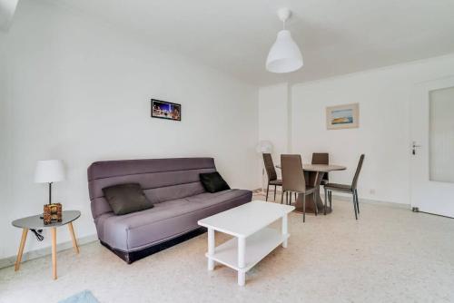 un salon avec un canapé violet et une table dans l'établissement CERES- Juan les Pins - 200m des plages, 4pers, wifi, ,clim, parking, à Juan-les-Pins