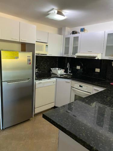 a kitchen with white cabinets and a stainless steel refrigerator at Playa Guacuco - Views and Beach Access in Playa Guacuco