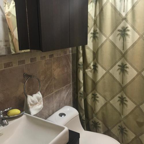a bathroom with a sink and a shower curtain with palm trees at Playa Guacuco - Views and Beach Access in Playa Guacuco