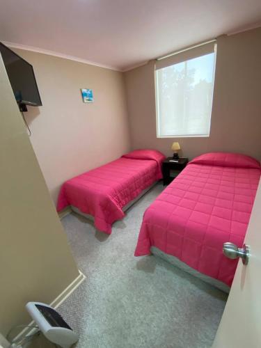 two beds in a room with pink sheets and a window at Laguna Bahía Mar y Campo in San Antonio