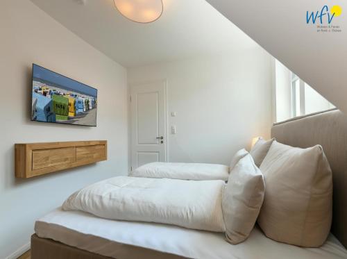 a bedroom with two beds and a tv on the wall at Haus Christine Ferienwohnung 4 in Langeoog