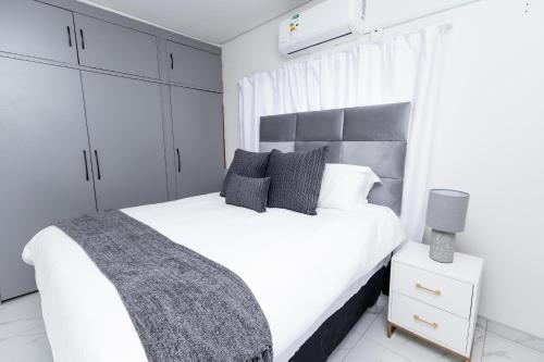 a bedroom with a white bed and white cabinets at Gaborone City Center stay, ultrafast wifi & near CBD & Airport in Joverega