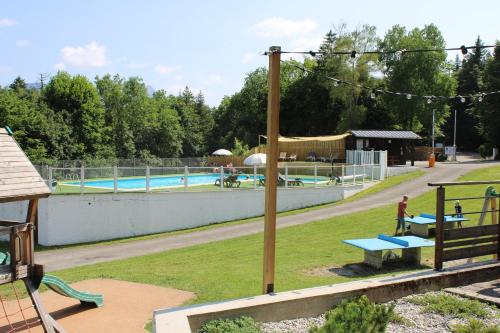 an outdoor swimming pool with a picnic table and benches at Camping Le Balcon de Chartreuse in Miribel-les-Échelles