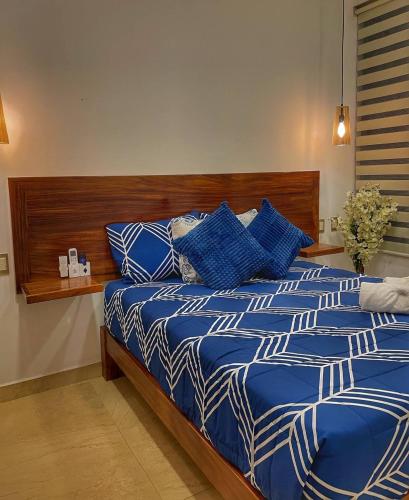 a bed with blue and white sheets in a bedroom at Casa Bonita PXM in Puerto Escondido