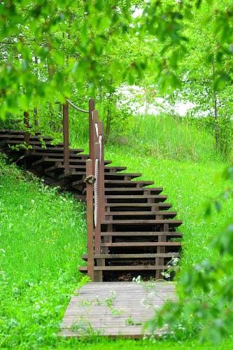 a wooden staircase in a field with green grass at Wytwórnia Ciszy i Spokoju Apartamenty Wojtokiemie in Puńsk