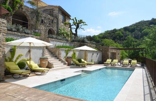une piscine avec chaises et parasols à côté d'un bâtiment dans l'établissement Le Vaquier, à Soudorgues