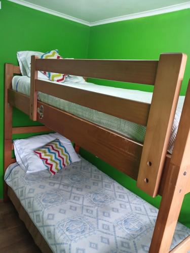 two bunk beds in a room with green walls at Cabaña con tinaja de hidromasaje in Valdivia