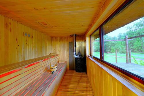 a wooden room with benches and a large window at Wytwórnia Ciszy i Spokoju Apartamenty Wojtokiemie in Puńsk